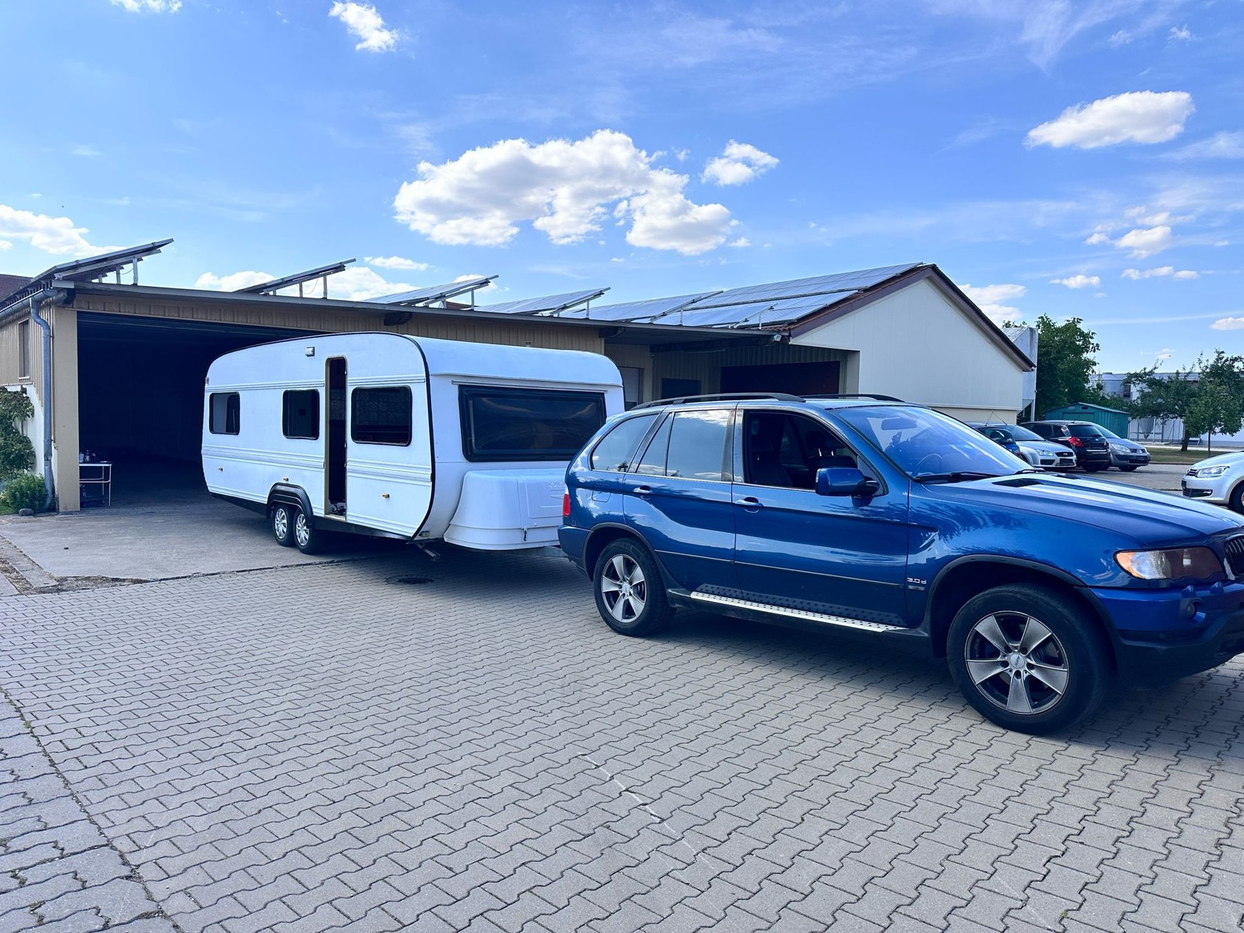 Der Caravan am blauen BMW X5 vor der Halle